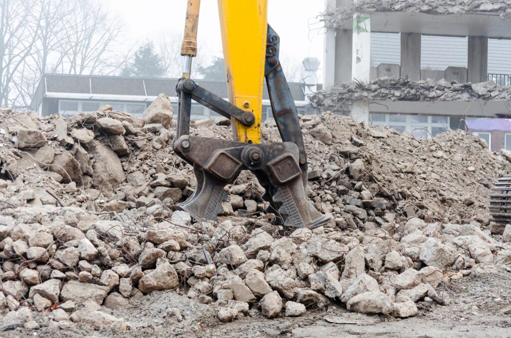 Demolition Bryan-College Station Texas - Debris Cleanup 2 "a pile of rubble with a yellow machine in the background"